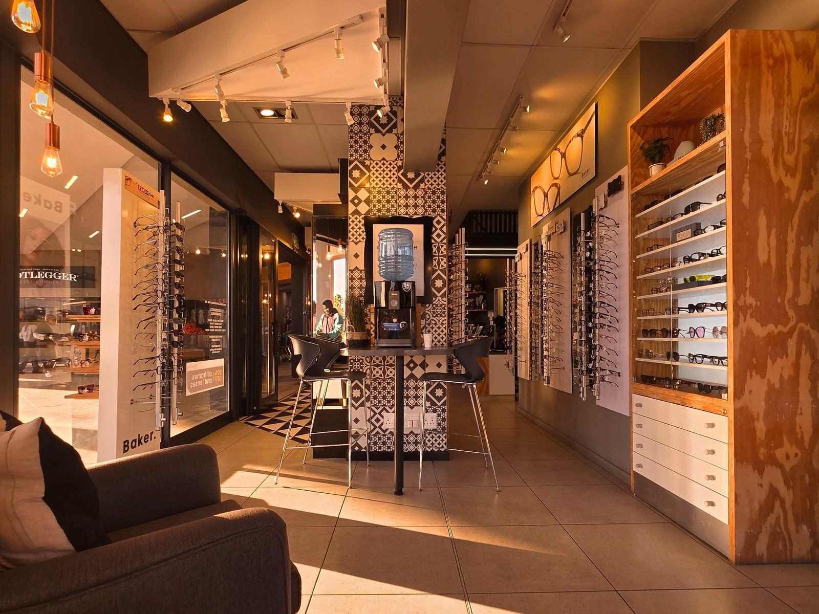 The inside of a modern optical store with walls of frames and a seating area.